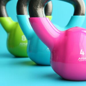 Vibrant colored kettlebells on blue background highlighting fitness and exercise equipment.